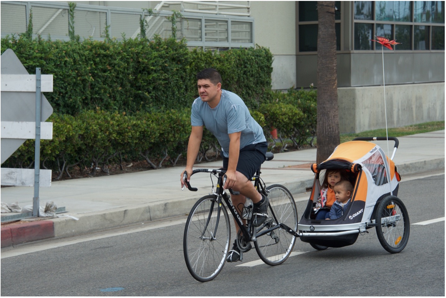man riding a bike with a trailer containing two children